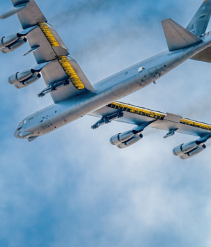 Steel military plane flying against a clear blue sky and light clouds