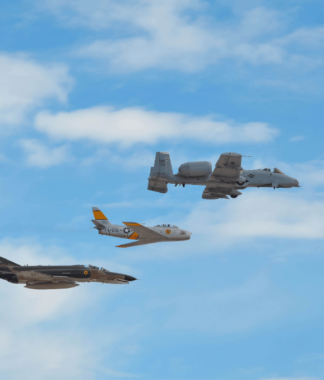 3 military planes flying alongside each other in a blue sky with clouds